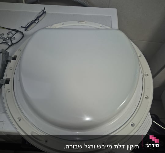 דלת מכונת כביסה מפורקת לצורך תיקון או החלפת ציר